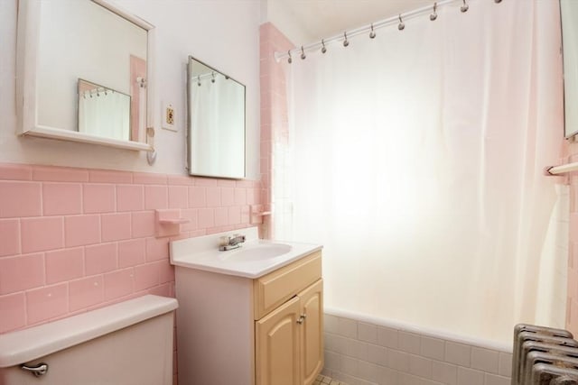 bathroom featuring a wainscoted wall, vanity, tile walls, and radiator heating unit