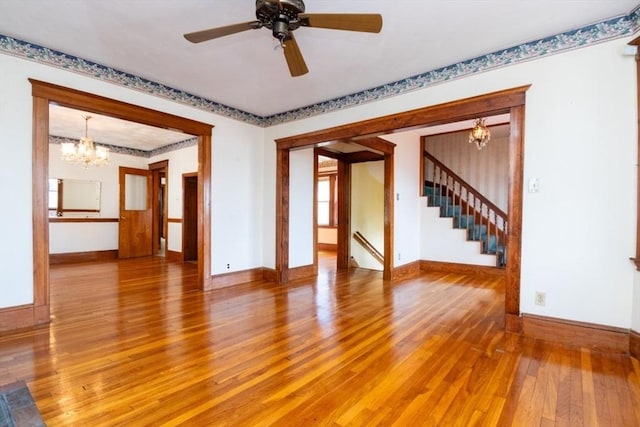 unfurnished room with stairs, light wood-style floors, and baseboards