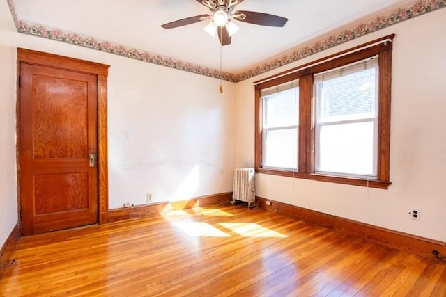 unfurnished room with baseboards, light wood-style floors, ceiling fan, and radiator heating unit