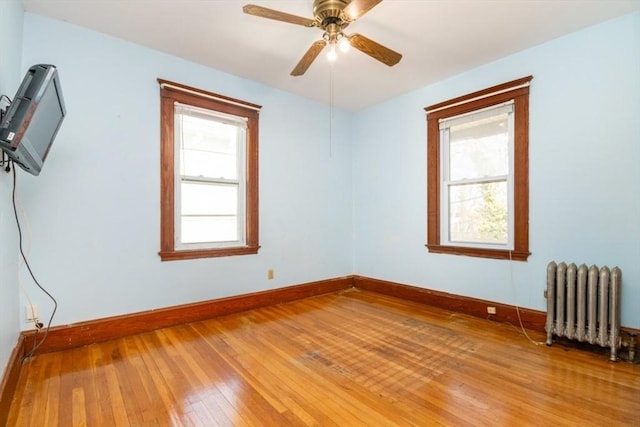 spare room featuring plenty of natural light, radiator, light wood-type flooring, and baseboards