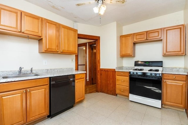 kitchen with wooden walls, black dishwasher, range with gas stovetop, wainscoting, and a sink