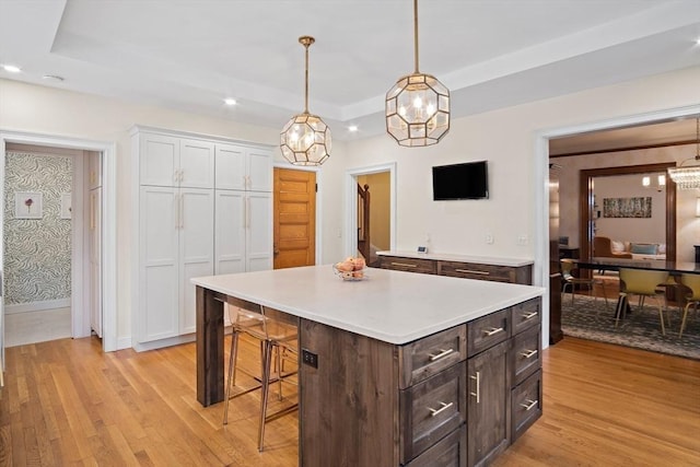 9 Arlington Rd, Woburn, MA 01801 - kitchen featuring light wood-type flooring, white cabinetry, a breakfast bar area, a raised ceiling, and recessed lighting