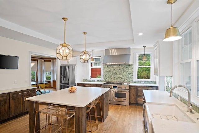 9 Arlington Rd, Woburn, MA 01801 - kitchen featuring stainless steel appliances, wall chimney range hood, backsplash, a breakfast bar area, and light countertops