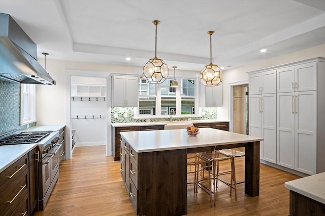 9 Arlington Rd, Woburn, MA 01801 - kitchen featuring double oven range, wall chimney range hood, light countertops, a kitchen breakfast bar, and tasteful backsplash