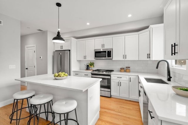 123-125 Centre St Unit Th4, Boston, MA 02124 - kitchen featuring backsplash, a sink, light wood finished floors, a breakfast bar, and stainless steel appliances