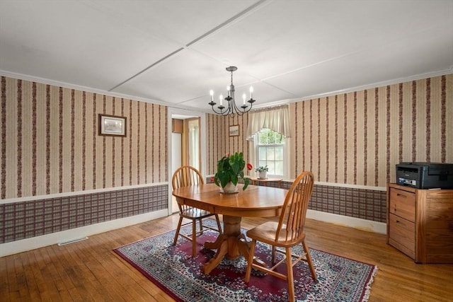 19 E St, Grafton, MA 01536 - dining area featuring wallpapered walls, wood-type flooring, a chandelier, a wainscoted wall, and ornamental molding