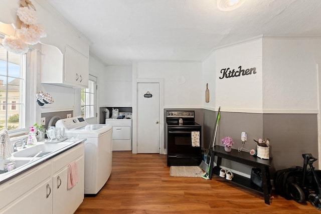 85 Everett St, Southbridge, MA 01550 - kitchen with black electric range, washing machine and dryer, white cabinets, light wood finished floors, and light countertops