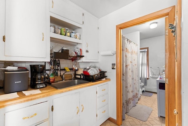 kitchen featuring tasteful backsplash, white cabinetry, and a sink