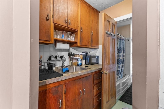 kitchen featuring black microwave, brown cabinets, and backsplash