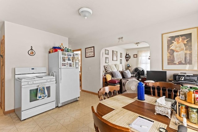 dining room with light floors, baseboards, and arched walkways