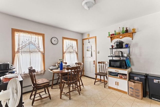 dining room featuring a baseboard heating unit, light floors, and baseboards