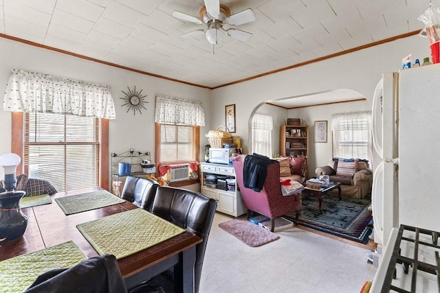 dining space featuring arched walkways, ceiling fan, ornamental molding, and tile patterned floors