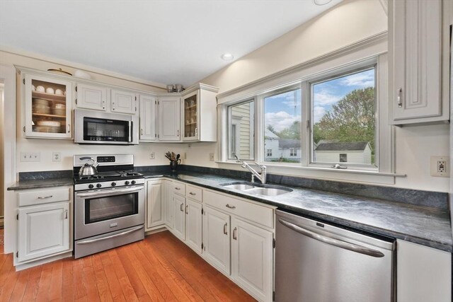 39 Cook Rd, Southampton, MA 01073 - kitchen featuring appliances with stainless steel finishes, a sink, dark countertops, glass insert cabinets, and light wood finished floors