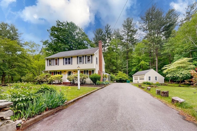 79 Charter Rd, Acton, MA 01720 - colonial-style house with an outdoor structure, a chimney, a detached garage, a front lawn, and covered porch