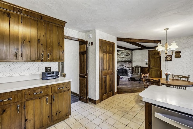 kitchen featuring light tile patterned flooring, beam ceiling, light countertops, wallpapered walls, and decorative light fixtures