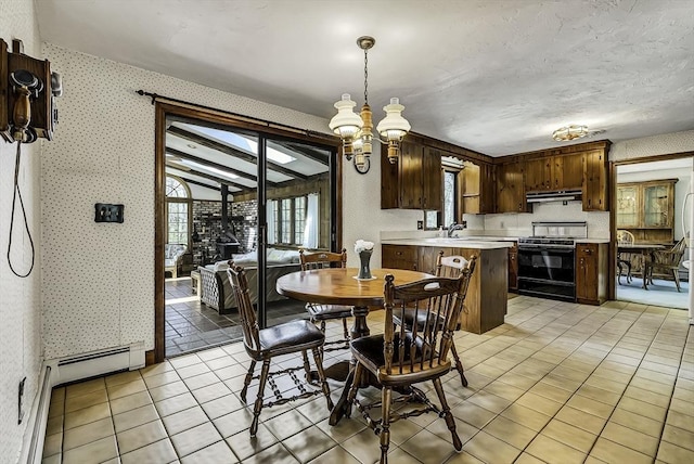 dining space featuring an inviting chandelier, a baseboard radiator, light tile patterned floors, and wallpapered walls