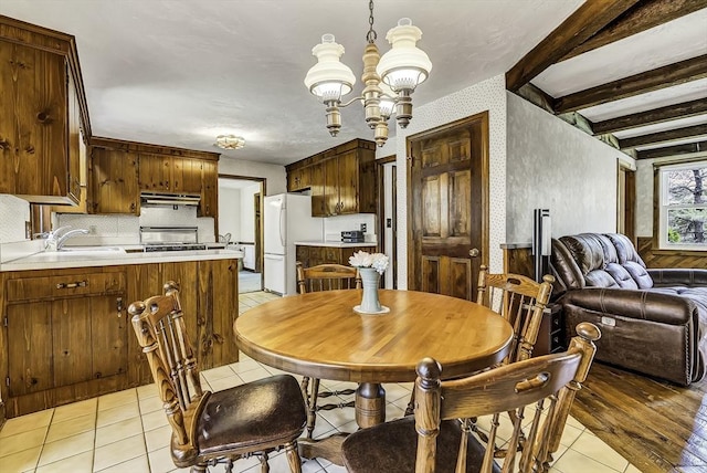 dining space with beamed ceiling, wallpapered walls, light tile patterned flooring, and a notable chandelier