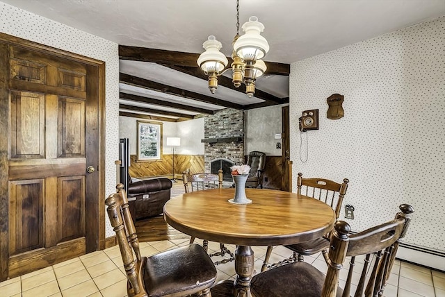 dining room with a stone fireplace, beam ceiling, light tile patterned floors, a chandelier, and wallpapered walls
