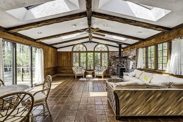 sunroom / solarium featuring a wood stove, beam ceiling, and a skylight