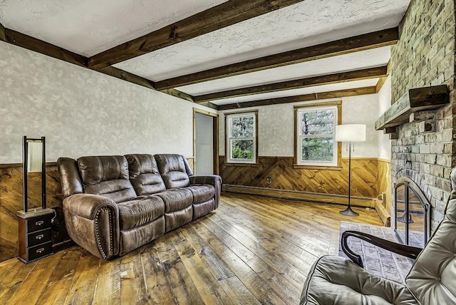 living room featuring wood-type flooring, a fireplace, beamed ceiling, wooden walls, and a wainscoted wall