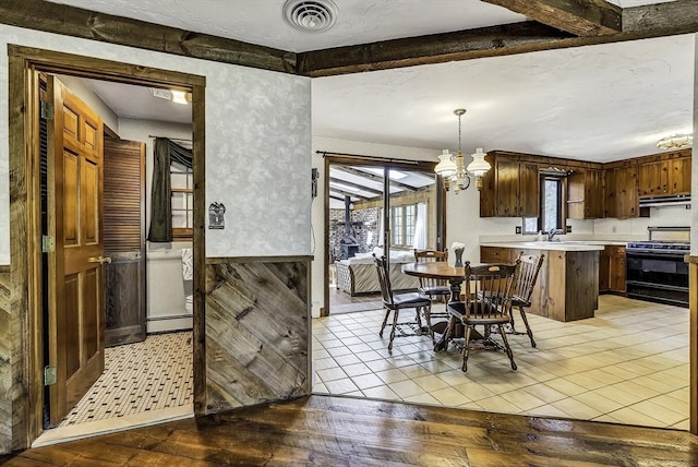 dining room with light wood-style floors, a chandelier, a baseboard heating unit, beamed ceiling, and visible vents