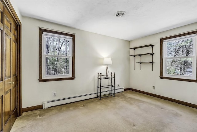 spare room featuring baseboards, a baseboard heating unit, visible vents, and light carpet