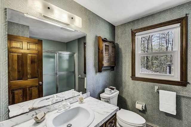 bathroom with vanity, wallpapered walls, toilet, and a shower stall