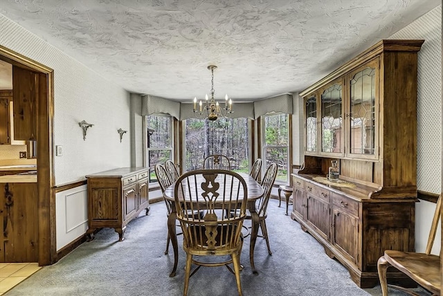 dining area with a notable chandelier, wainscoting, a textured ceiling, carpet, and wallpapered walls