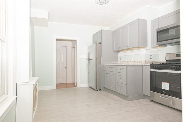 kitchen with appliances with stainless steel finishes, gray cabinets, and crown molding