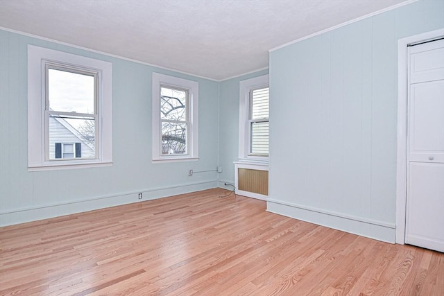 empty room featuring crown molding, radiator heating unit, and light hardwood / wood-style floors