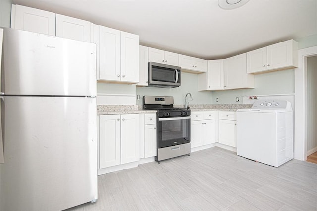 kitchen with washer / clothes dryer, white cabinets, and stainless steel appliances