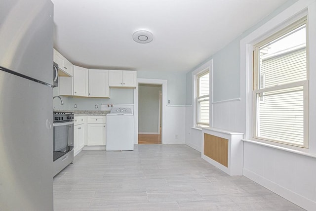 kitchen featuring white cabinets, washer / dryer, and stainless steel appliances