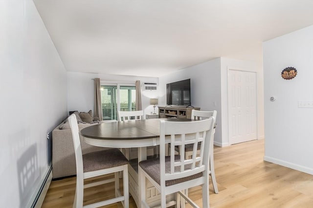 dining space with baseboard heating and light hardwood / wood-style flooring