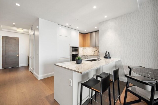 240 Devonshire St Unit 4210, Boston, MA 02110 - kitchen with a sink, modern cabinets, baseboards, a kitchen bar, and a peninsula