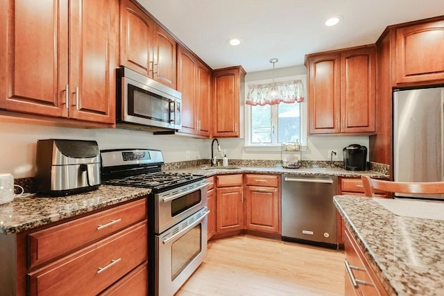 421 Gray Ter, Dighton, MA 02764 - kitchen featuring appliances with stainless steel finishes, a sink, light stone counters, light wood-style flooring, and decorative light fixtures
