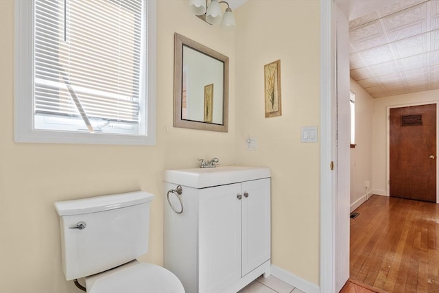 bathroom with visible vents, baseboards, toilet, wood finished floors, and vanity