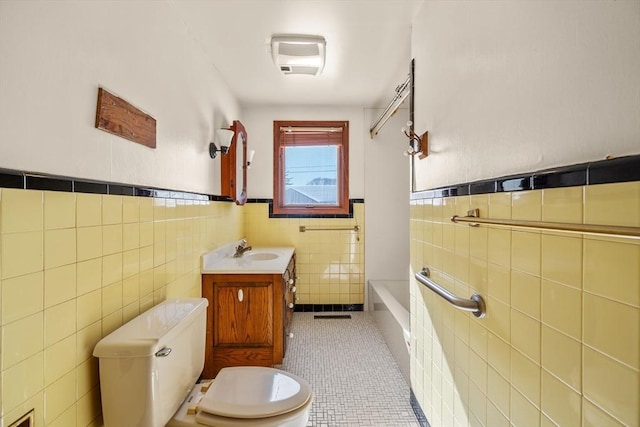 full bath with tile walls, toilet, wainscoting, tile patterned floors, and vanity