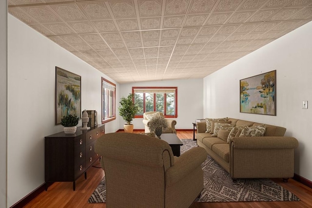 living room with an ornate ceiling, baseboards, and wood finished floors