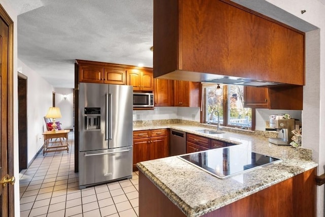 kitchen with sink, appliances with stainless steel finishes, light tile patterned flooring, light stone counters, and kitchen peninsula