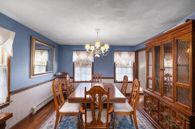 dining space featuring a textured ceiling, an inviting chandelier, baseboard heating, and dark wood-type flooring