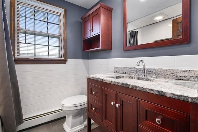 bathroom featuring tile patterned flooring, a baseboard heating unit, toilet, vanity, and tile walls