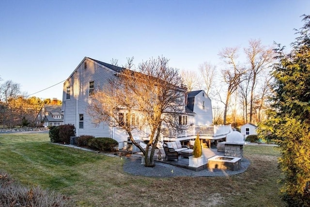 back of property featuring a lawn, a deck, and a patio