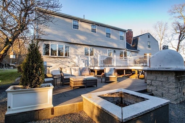 back of property with an outdoor living space with a fire pit, a patio, a deck, and exterior kitchen