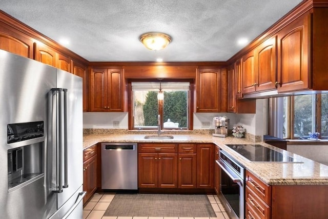 kitchen with sink, light stone countertops, light tile patterned floors, a textured ceiling, and stainless steel appliances