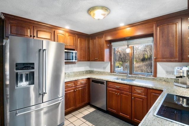 kitchen featuring sink, light stone countertops, a textured ceiling, light tile patterned floors, and appliances with stainless steel finishes