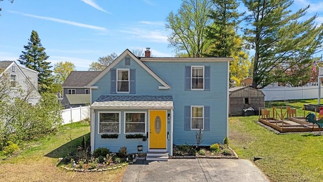 view of front facade with a garden, fence, a front yard, a chimney, and entry steps