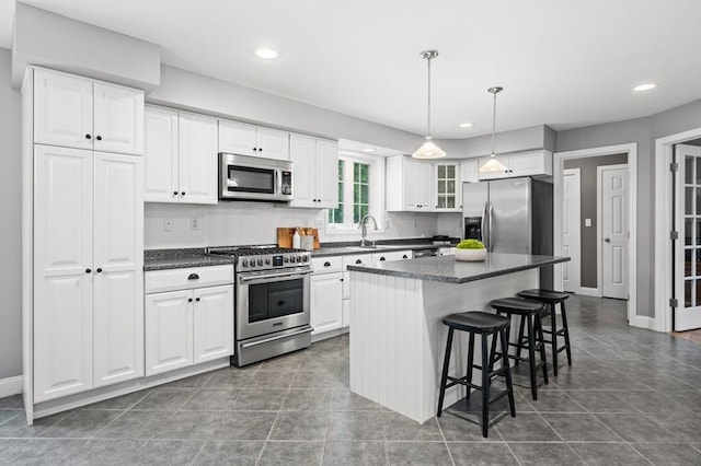 100 Overlook Ter, Dracut, MA 01826 - kitchen with stainless steel appliances, dark countertops, a breakfast bar, a kitchen island, and white cabinetry