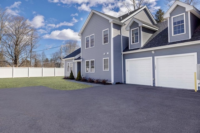 view of property exterior with a yard, fence, a garage, and driveway