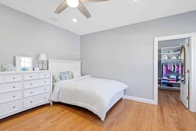 bedroom featuring visible vents, light wood-style flooring, a walk in closet, and a closet