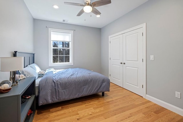 bedroom with a closet, light wood-type flooring, baseboards, a ceiling fan, and visible vents